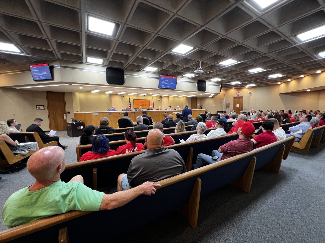 Members of the public fill the seats of the Council Chambers as they watch the Council conduct a meeting from the dais. 