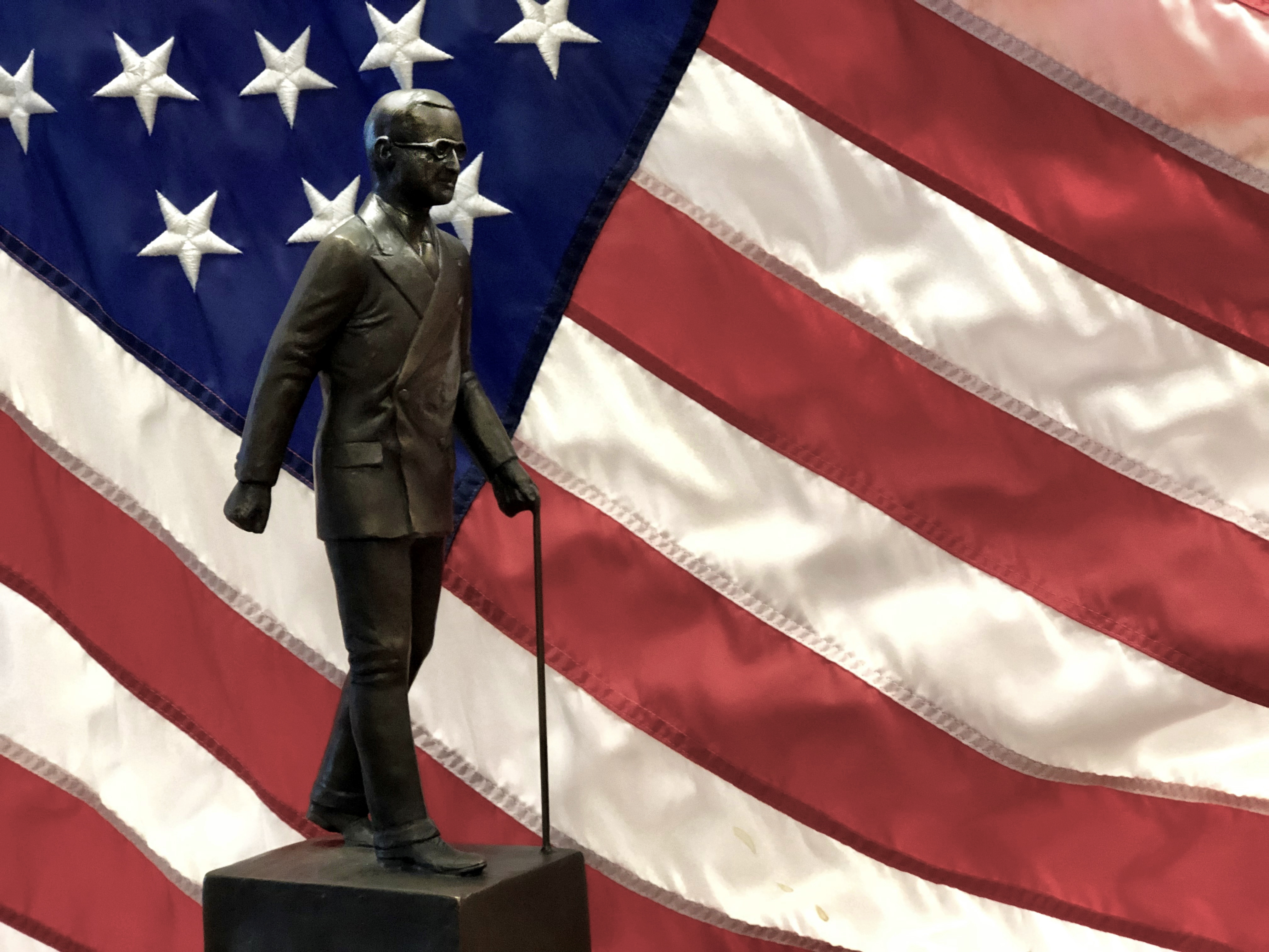 Harry S. Truman Public Service Award in which President Truman is depicted in a suit walking with his cane, in front of an American Flag.