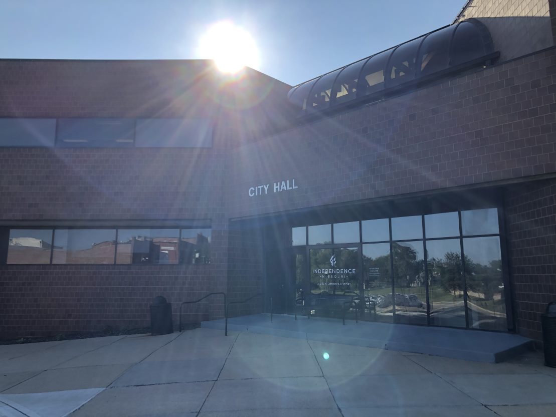 Independence City Hall, a brick building, is lit by the sun from behind