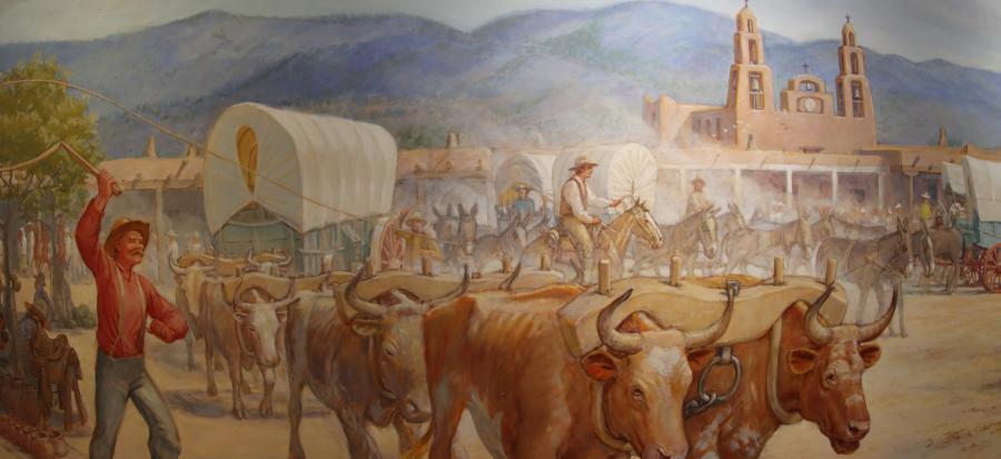 Image of a mural depicting pioneers heading west with oxen pulling a covered wagon on a dirt road and activity behind them. 