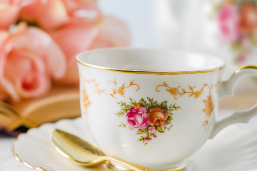 Image of a cup of tea with a bouquet of roses in the background. 