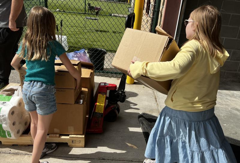 Two children carrying donations into the shelter.