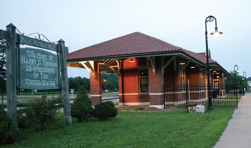 Outside image of the Truman Depot with lights on. Truman Depot sign in foreground and lamppost to the right with the Depot in the center.