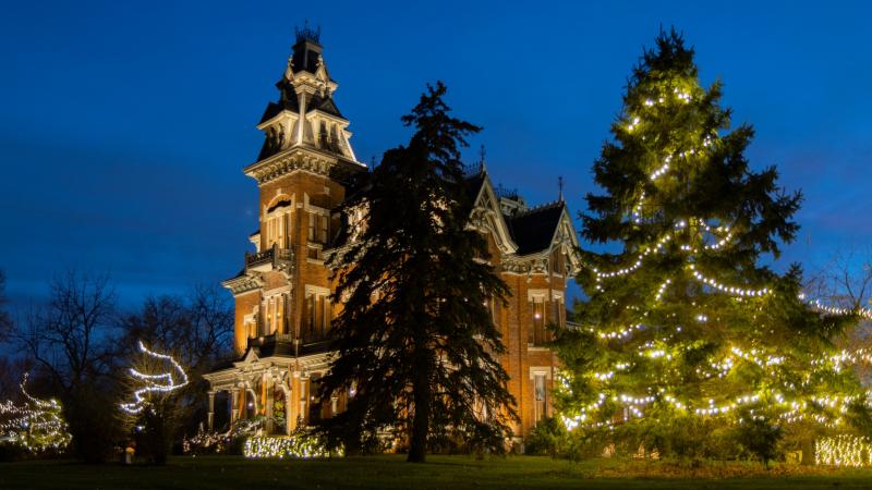 Side view exterior image of the Vaile Mansion with holiday lights on.