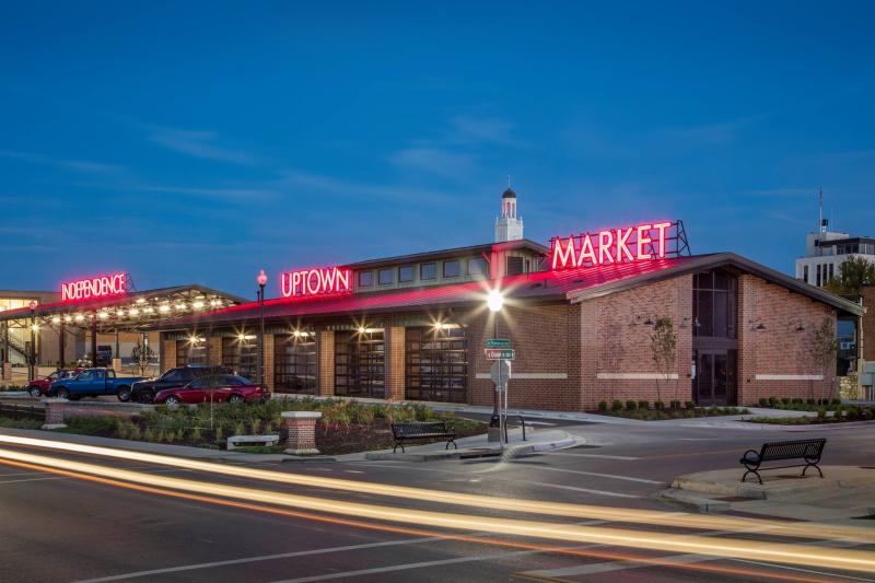 A long outdoor market with red neon writing that read 'Indpendence Uptown Market'