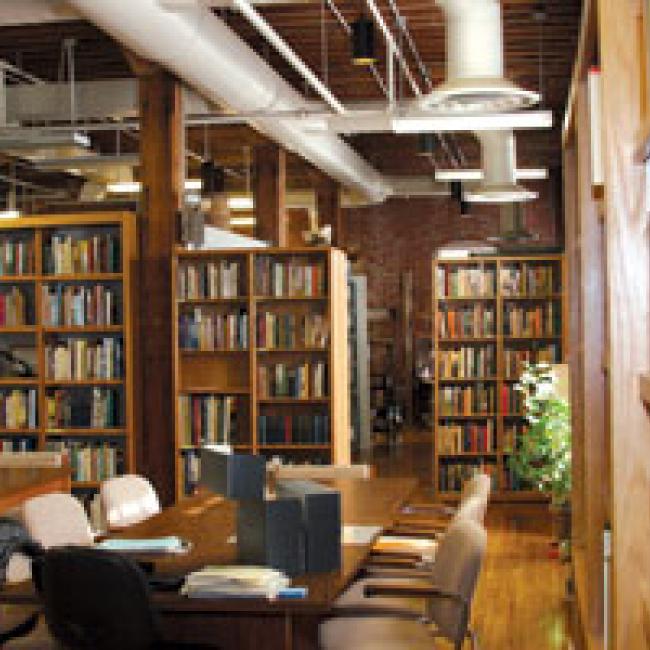 A picture of the interior of a library with bookshelves and chairs